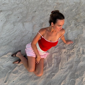 Detailed view of women's red camisole and pink skirt set on a sunny beach setting
