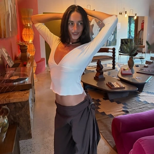 Close-up of a white deep V-neck backless crop top paired with grey wide-leg trousers