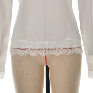 Detail of elegant white long sleeve top featuring delicate eyelash lace trim at the hem