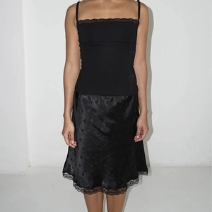 Dettaglio del camisole nero con pizzo e gonna in raso con jacquard a pois chic