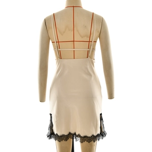 Detail of elegant beige satin slip dress featuring delicate black lace trim at the hem