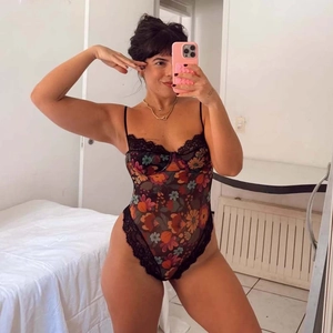Détail d'un body à fleurs avec bordure en dentelle noire et fines bretelles