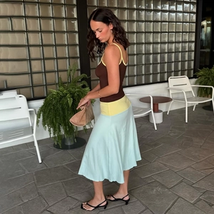 Detail of color-block dress with brown bodice, yellow waist, and light blue satin skirt