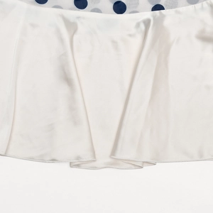 Detail aus Satinstoff mit Punktemuster und feinem Rollsaum an einem schicken Kleid