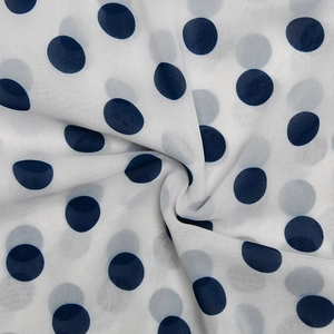 Detailaufnahme von weißem Chiffonstoff mit marineblauen Punkten und weichen Falten