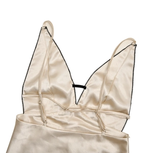 Detail of champagne satin dress featuring deep V-neck and black contrast stitching