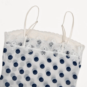 Nahaufnahme eines weißen Polka-Dot-Camisole mit feiner Spitze und verstellbaren Trägern