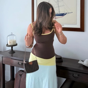 Close-up of slim contrast camisole paired with a light blue maxi skirt and chain bag