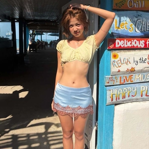 Detail of light blue mini skirt with red lace trim and yellow puff sleeve crop top