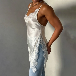 Detailed side view of white satin camisole with lace trim and high side slit detail