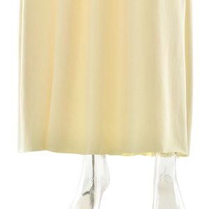 Detailed view of the light yellow flowing hem of a sleeveless V-neck maxi dress