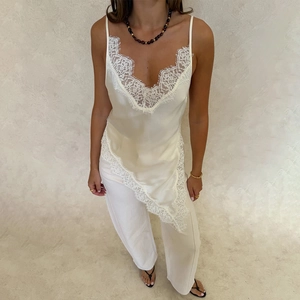 Close-up of elegant cream satin camisole featuring delicate white lace trim and V-neck