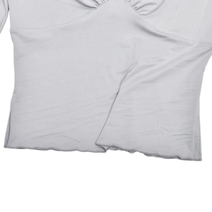 Close-up of light gray top featuring V-neck pleats and lettuce edge hem details