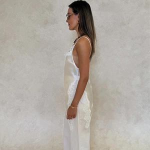 Detailed close-up of cream satin slip dress featuring delicate white lace patchwork and silk texture