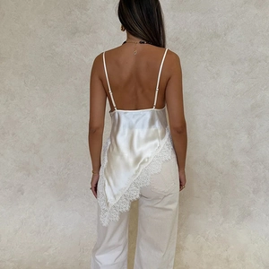 Detail of white satin dress featuring open back, thin straps, and lace trim hem