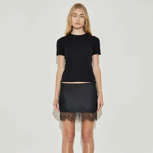 Close-up detail of the elegant eyelash lace trim and satin fabric on the black mini skirt
