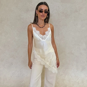 Detail of white satin camisole with deep V-neck and exquisite floral lace trim