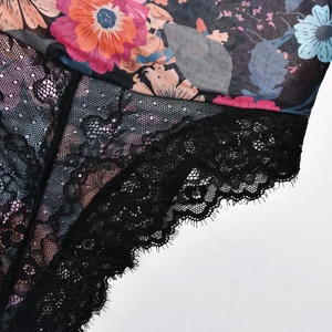 Détail d'un body en mesh floral avec bordure en dentelle noire et cils délicats