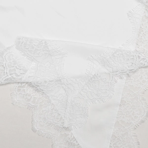 Detailed view of delicate eyelash lace trim and smooth white satin fabric texture