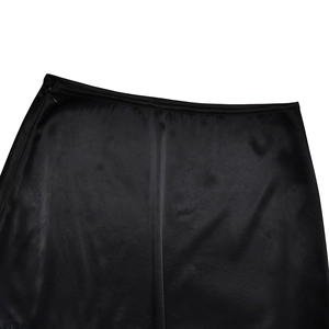 Detail of high-waisted black satin mini skirt showing side invisible zipper and silky texture
