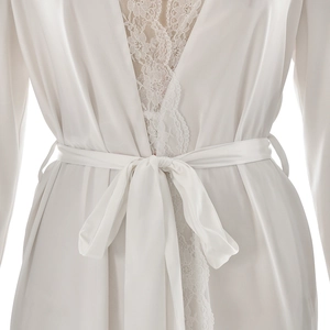 Detail of white silk robe featuring intricate floral lace trim and elegant waist tie closure