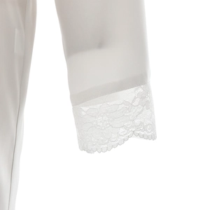 Close-up of elegant floral lace trim on the cuffs of a white satin lounge robe