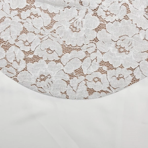 Nahaufnahme von weißem Blumen-Spitzenmuster mit hautfarbenem Futter an einem Abendkleid