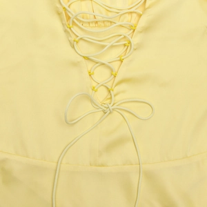 Détails de la robe dos nu jaune avec lacets croisés et nœud papillon élégant