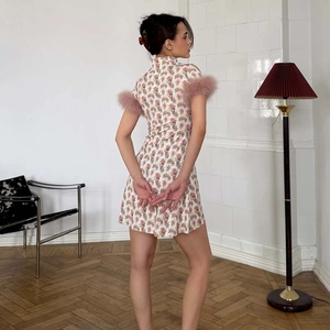 Détail de mini robe fleurie rose avec poignets en fausse fourrure et col haut élégant