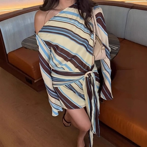 Detail of striped asymmetric dress featuring cold shoulder neckline and waist tie knot