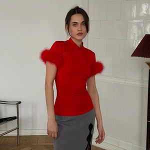 Detailed close-up of feather-trimmed cuffs on a slim-fit red turtleneck short-sleeve top
