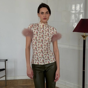 Detail of slim-fit floral top with mock neck and fluffy pink feather cuffs on sleeves