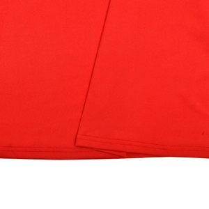 Détail de l'ourlet de la robe rouge à plumes avec une couture robuste à double aiguille