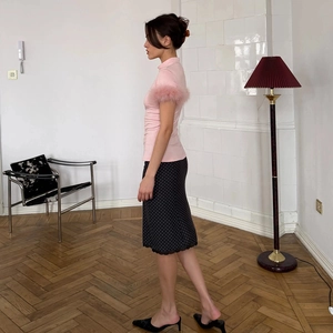 Detailed view of pink slim top with fluffy feather sleeves and a polka dot midi skirt
