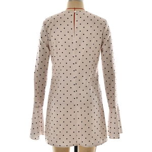 Détail arrière d'une robe en satin rose à pois avec manches évasées et bouton en perle
