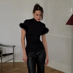 Detail of elegant black slim-fit high-neck top featuring luxurious feather trim on sleeves