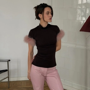 Close-up of black high-neck t-shirt featuring fluffy pink feather trim on short sleeves