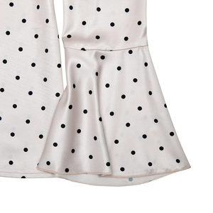 Détail du satin à pois montrant la texture soyeuse et le design élégant des manches à volants