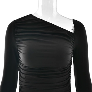 Close-up of ruched texture and asymmetric shoulder detail on a black bodycon dress