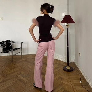 Detail of slim-fit turtleneck top with pink feather cuffs and back lace-up leather pants