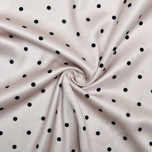 Détail du tissu satiné rose à pois noirs montrant la texture douce et le drapé de la soie