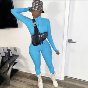 Detail of blue long-sleeve ribbed bodysuit showing zipper neckline and thumbhole cuff details