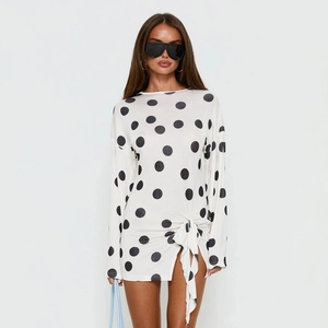 Dettaglio del mini abito bianco a maniche lunghe con pois neri e coulisse laterale