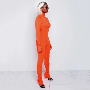 Close-up of bright orange ribbed jumpsuit with half-zipper collar and stacked leg details