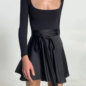 Dettaglio del top nero in maglia a scollo quadrato e gonna in raso con fiocco in vita