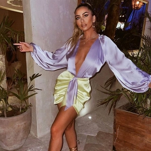 Detalle de minivestido satinado cruzado con mangas moradas y falda plisada verde
