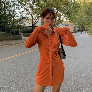Détail de la robe chemise orange à manches longues avec fronces et boutons sur le devant