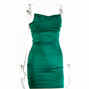 Détail de la robe moulante en satin vert émeraude montrant les plis et la texture soyeuse