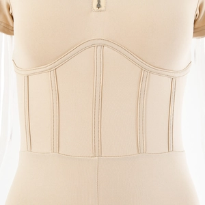 Detail of corset-style stitching and metal zipper on the waist of a slim beige bodysuit