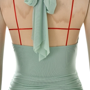 Dettaglio dell'abito in mesh verde chiaro con spalline rosse incrociate e vita arricciata